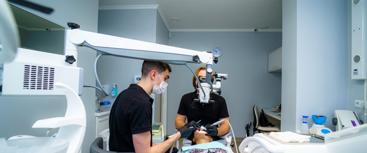 Two dentists examine the patient's teeth for the further treatment. Modern stomatology cabinet. Dentistry, medicine, medical equipment and stomatology concept.
